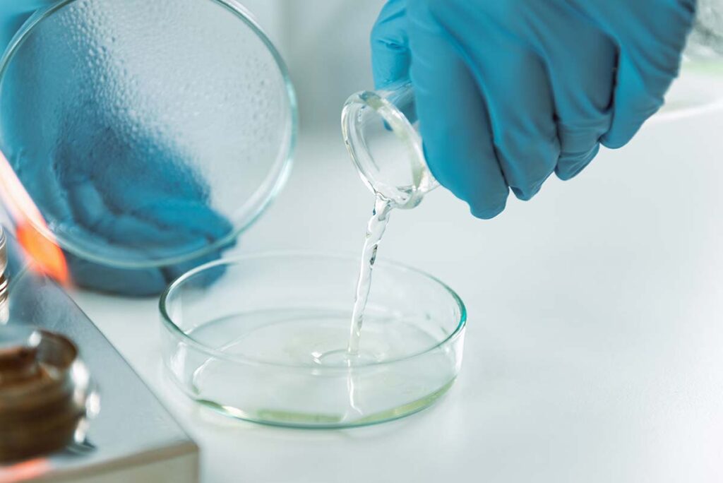 Laboratory technician pouring solution into petri dish during cannabis microbial testing, highlighting modern methods used when traditional decontamination fails.